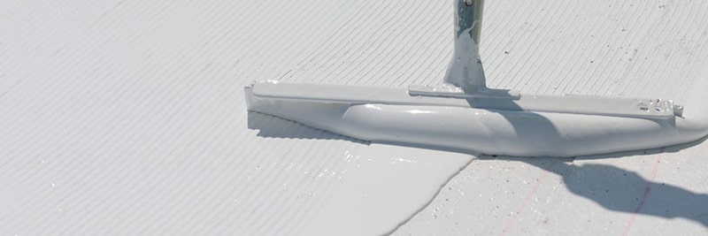 Une membrane de toiture épaisse et blanche appliquée par fluide est appliquée sur un toit