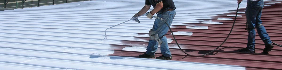 Les travailleurs appliquent une fine couche blanche de revêtement de toit pour restaurer un toit.